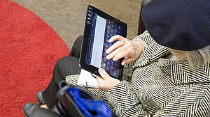 Eine ältere Frau aus der Vogelperspektive, die auf einem Tablet tippt