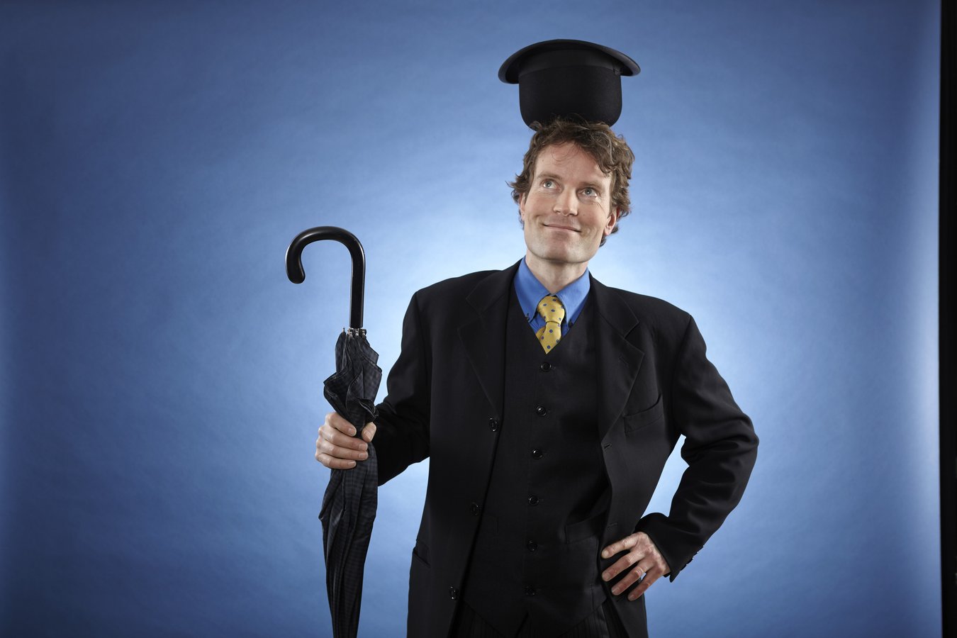 schwarz gekleideter Mann mit Regenschirm und Hut