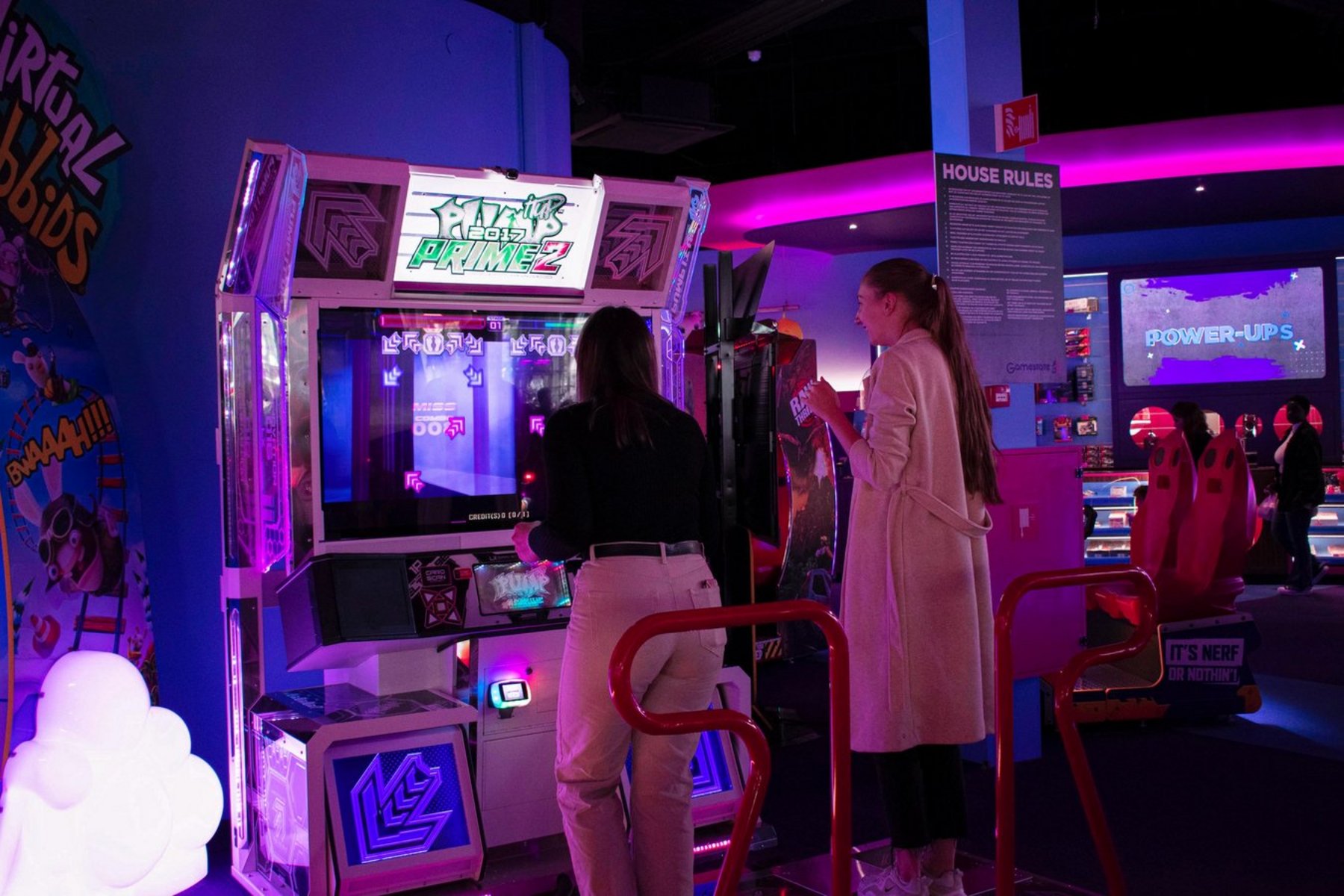 Zwei Menschen vor einem Videospielautomaten, die ein Tanzspiel spielen. 