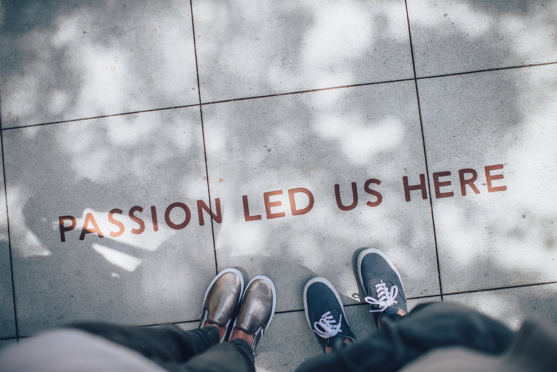 zwei Personen stehend; auf dem Boden die Wörter "Passion led us here"
