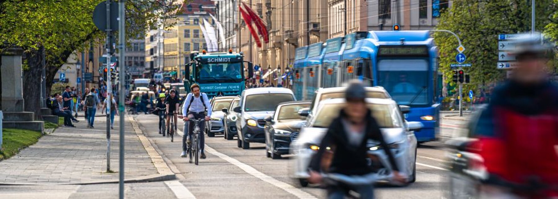 Fahrradfahrer, Autos und Straßenbahn auf einer Straße