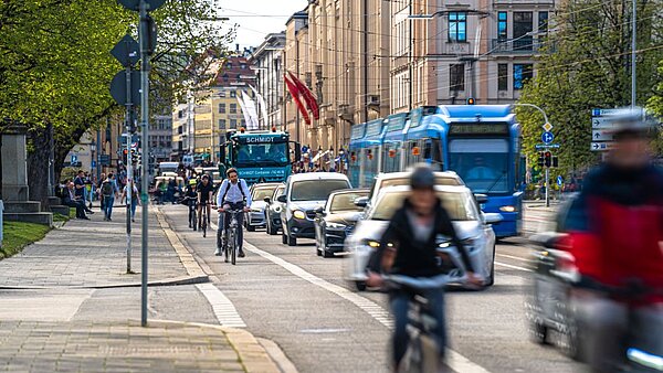 Fahrradfahrer, Autos und Straßenbahn auf einer Straße