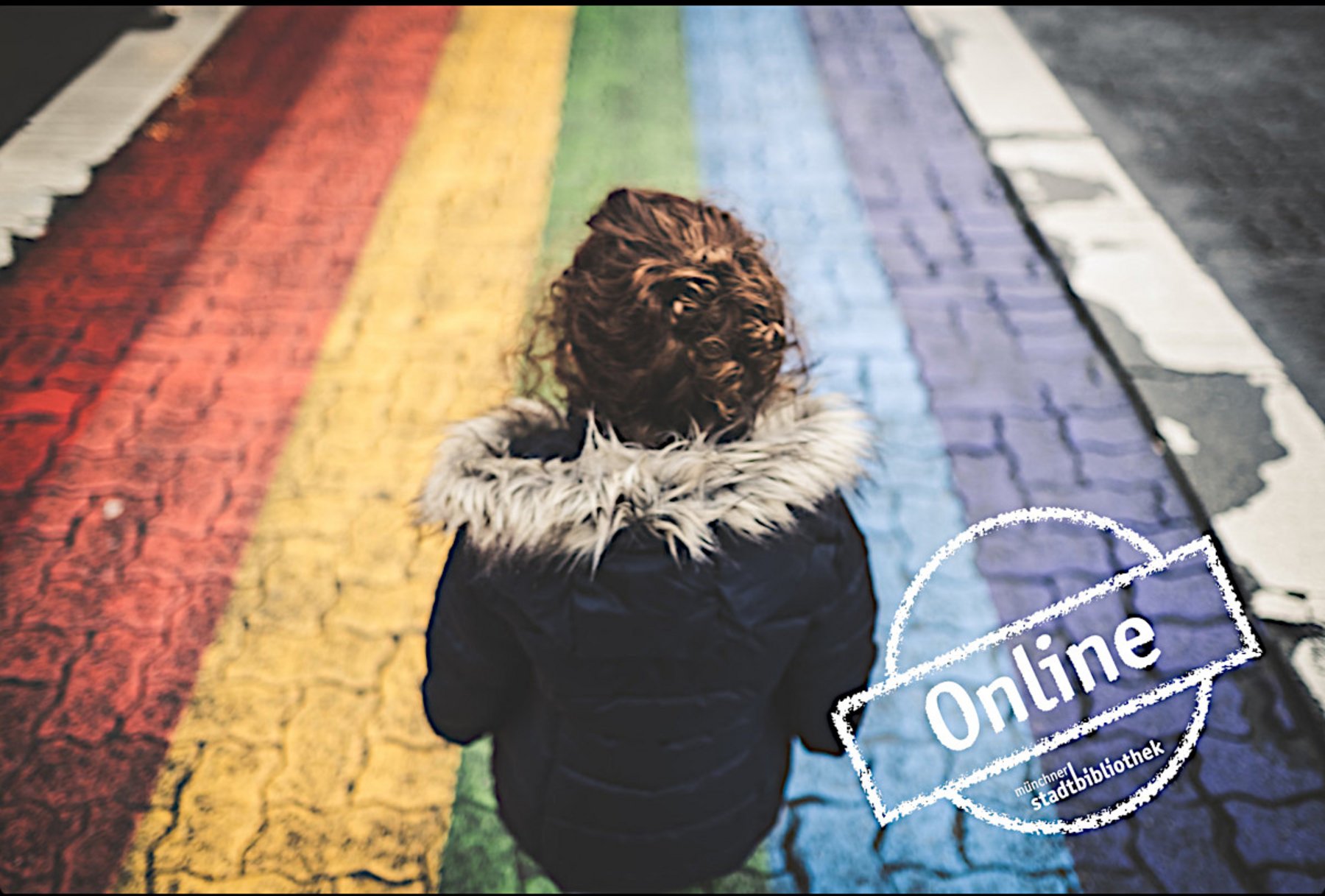 Rückenansicht eines Kindes auf einem als Regenbogen eingefärbten Gehweg