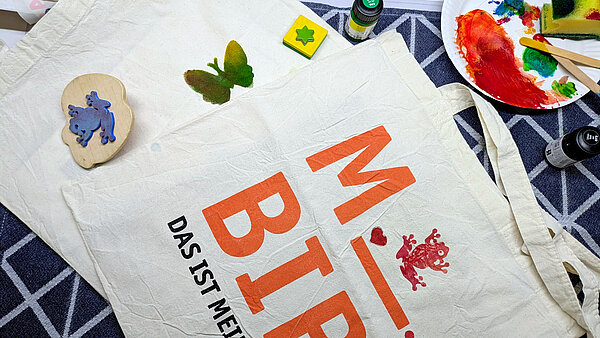 Stempel und Farben neben einer bedruckten Stofftasche