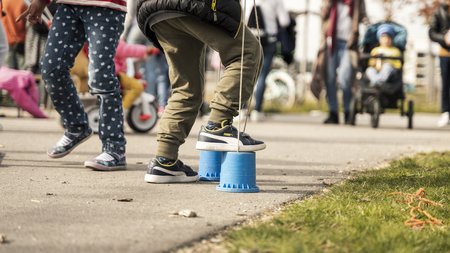 Kinder spielen mit Stelzen und Laufrädern