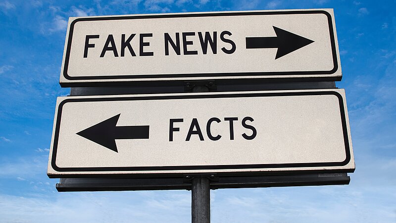 Zwei Schilder: Fake News, Pfeil nach rechts. Facts, Pfeil nach links.
