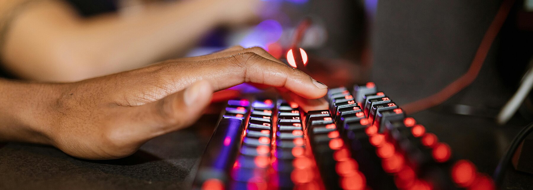 Eine Hand, die auf einer leuchtenden Tastatur liegt.