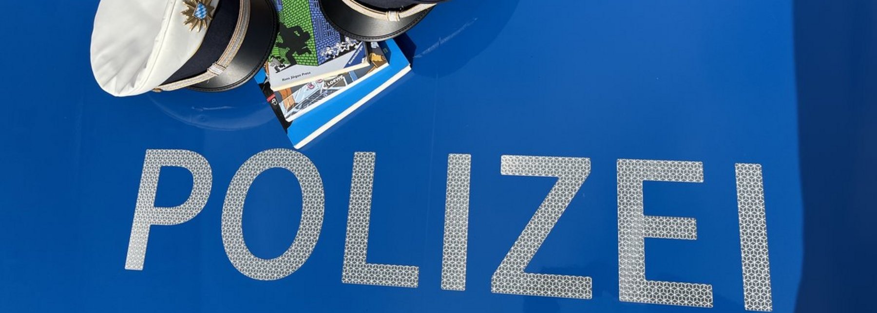 Polizeimützen und Bücher auf einem Polizeiauto