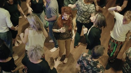 Ein Frau steht verloren zwischen Tanzenden auf der Tanzfläche