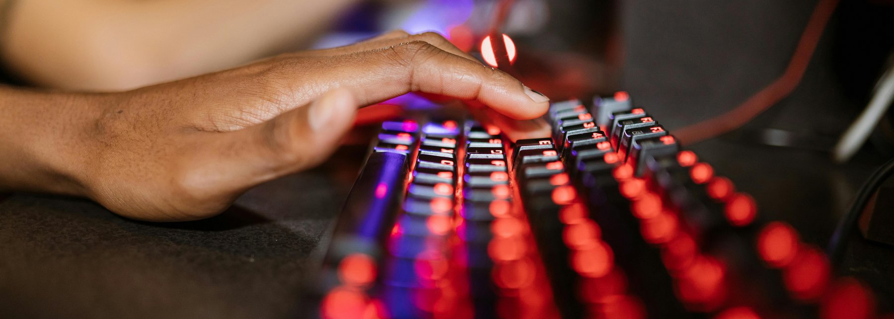 Eine Hand, die auf einer leuchtenden Tastatur liegt. 