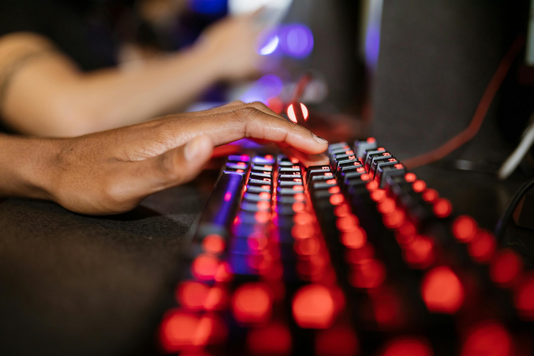 Eine Hand, die auf einer leuchtenden Tastatur liegt. 