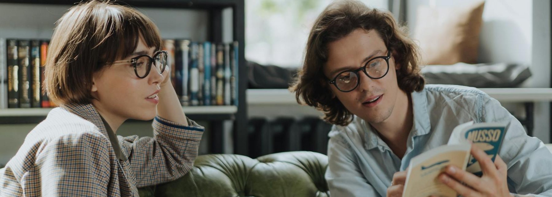 Frau und Mann sitzen mit Büchern auf grüner Couch