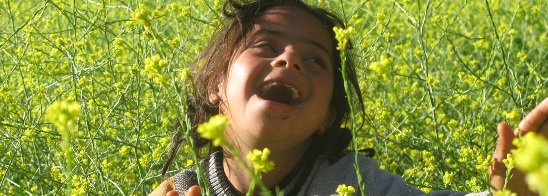 Strahlendes Mädchen mit Downsyndrom in Rapsfeld
