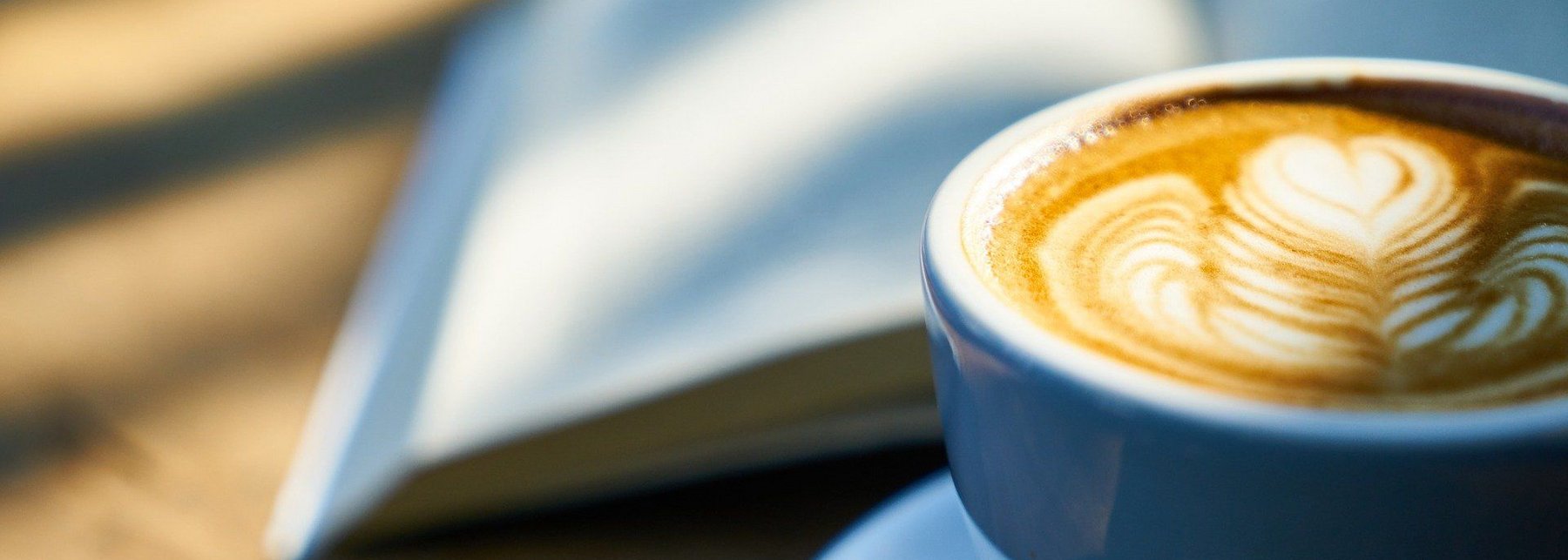 Kaffeetasse vor einem aufgeschlagenen Buch