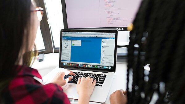 Zwei Frauen sitzen gemeinsam vor einem Computer