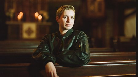 Frau sitzt auf Kirchenbank, im Hitnergrund ist der Altar zu sehen