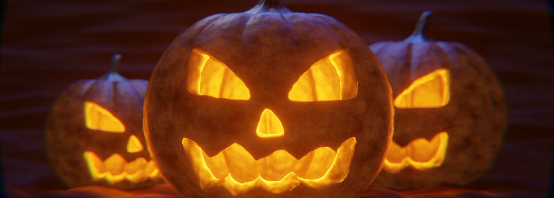 Drei Kürbisse mit geschnitzten Fratzen, die leuchten.