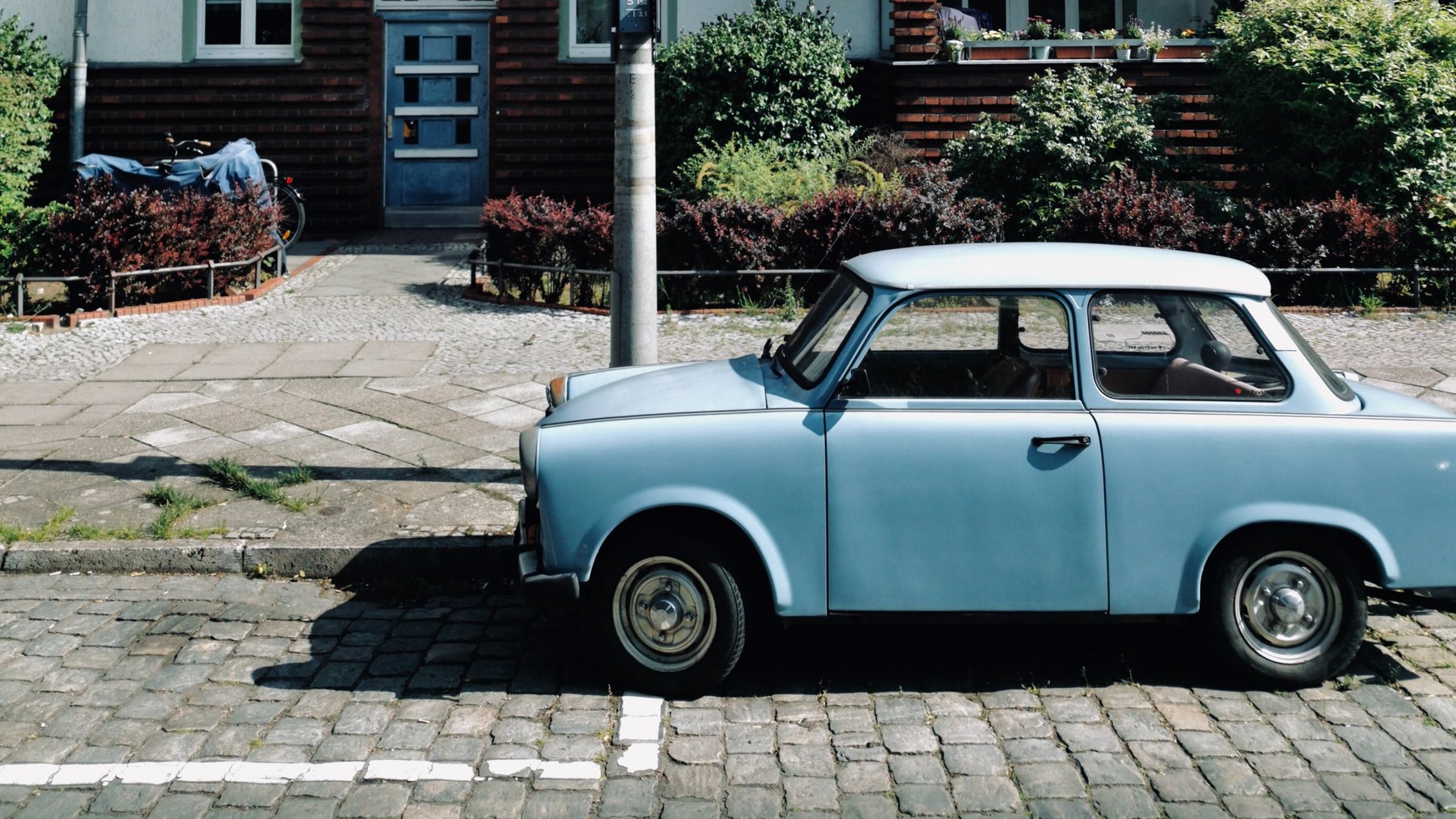 Himmelblauer Trabant vor einem Wohnhaus.