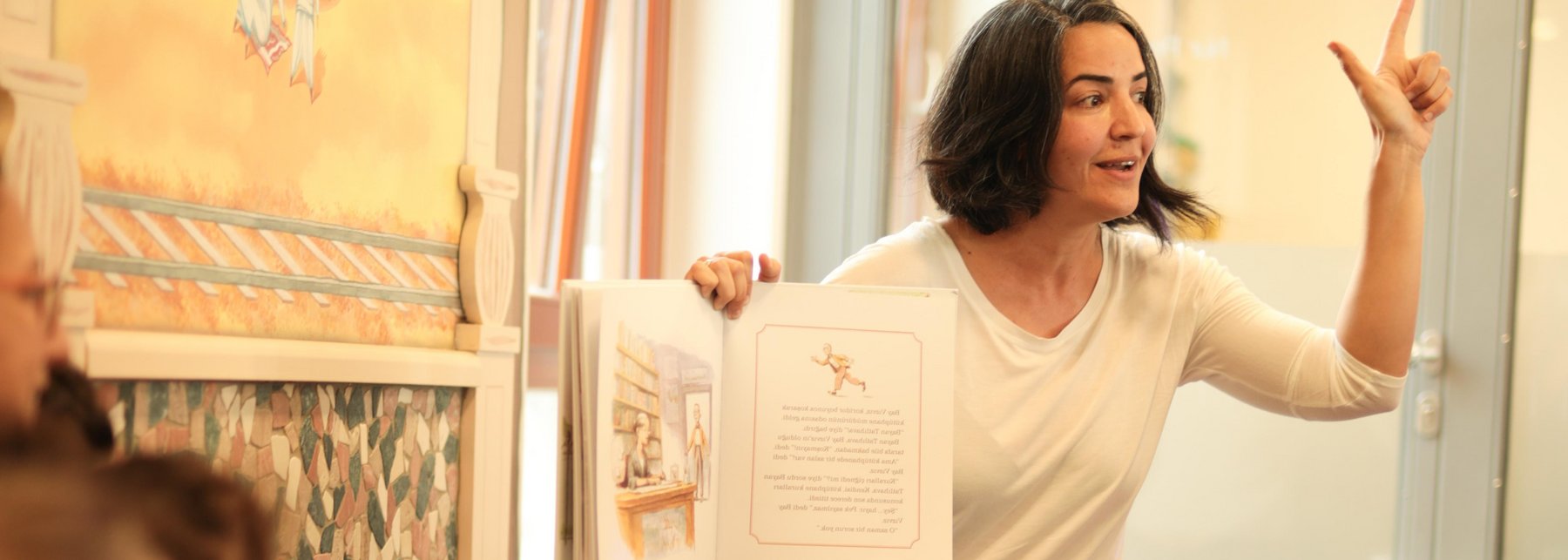 Frau zeigt ein Bilderbuch und liest vor