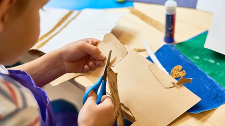 Kind mit Schere und Bastelmaterial