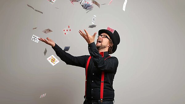 Zauberer Christaldo wirft Spielkarten in die Luft
