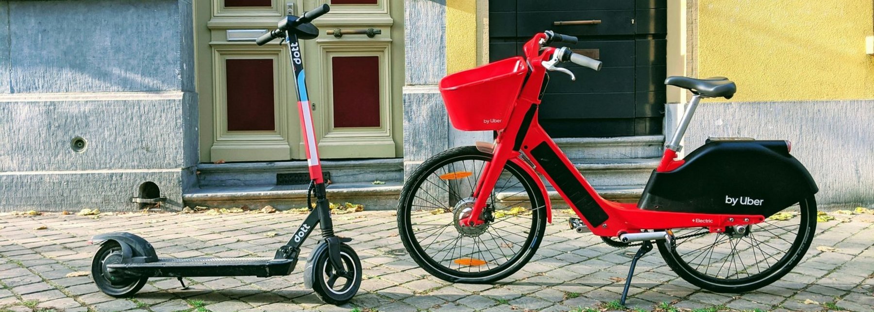 Ein Roller und ein Fahrrad stehen sich auf einem Gehweg gegenüber.
