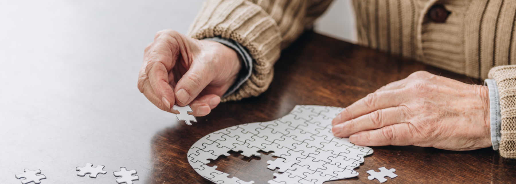 Eine ältere Person setzt ein Puzzle in Form eines Kopfes zusammen.