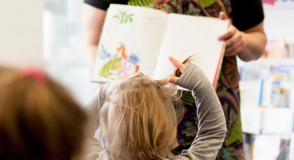 Kinder und eine Person mit einem Bilderbuch