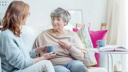 Zwei Frauen unterhalten sich auf einem Sofa.