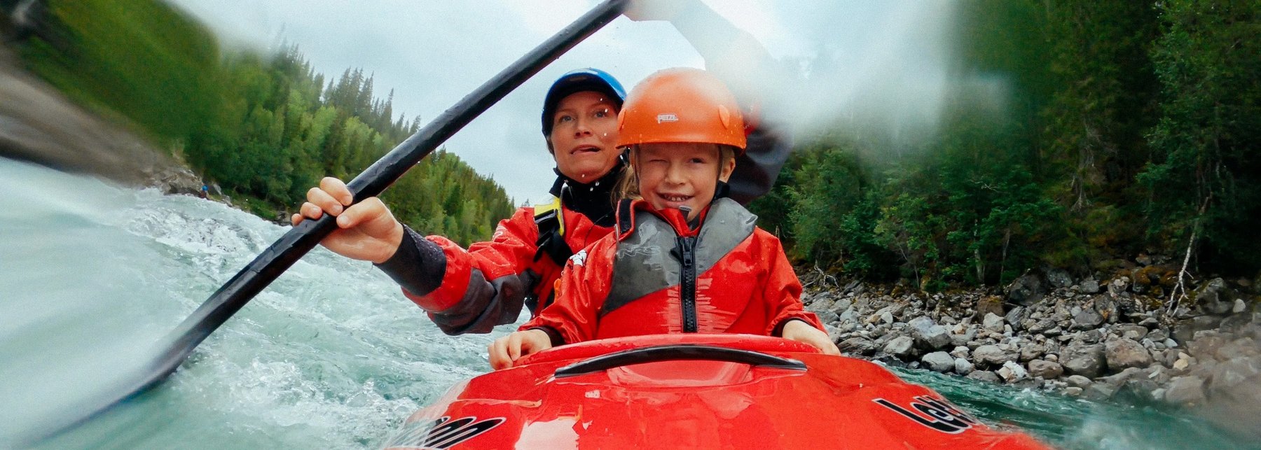Frau mit Kind im Kajak beim Wildwasserfahren